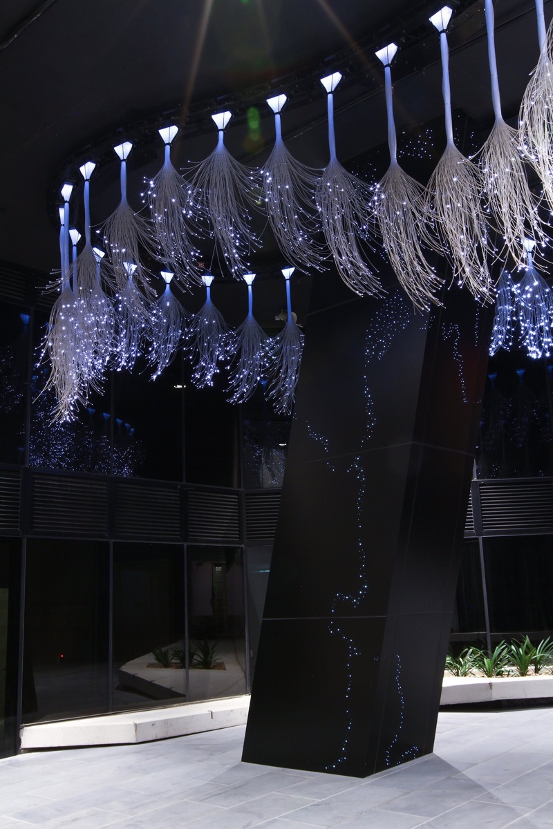 Rows of pendant fibre-optic tufts hanging from illuminated conical mounts above the Marina Tower walkway