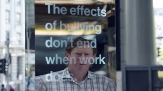 Close view of one mirrored column, the words 'The effects of bullying don't end when work does' set across the mirror