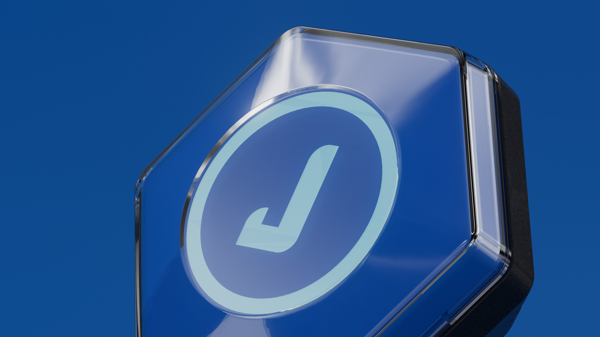 Close-up of a reader's glossy hexagonal faceplate, the Juniverse 'J' emblem glowing pale blue behind a clear cover