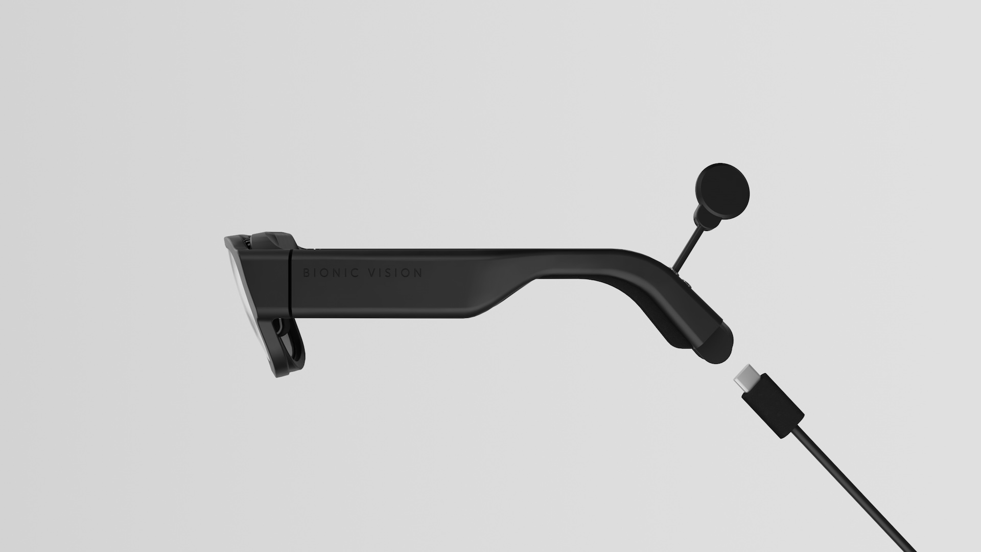 Side profile of the glasses: the transcutaneous coil on a short stalk behind the ear, with a USB-C tether to the pack