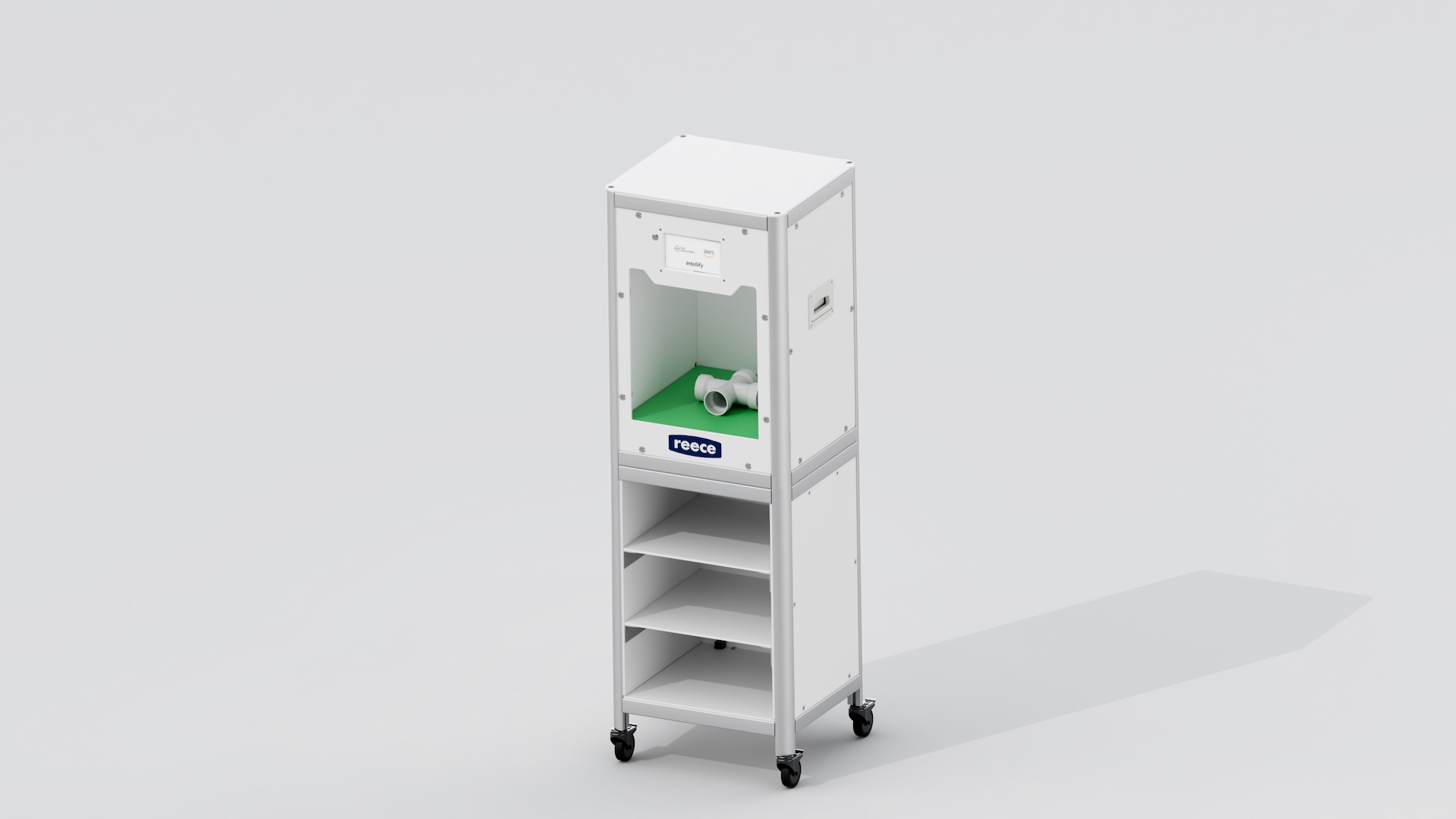 White cart on castors with a plumbing tee fitting on the chroma-key green floor of its scanning bay, storage shelves below