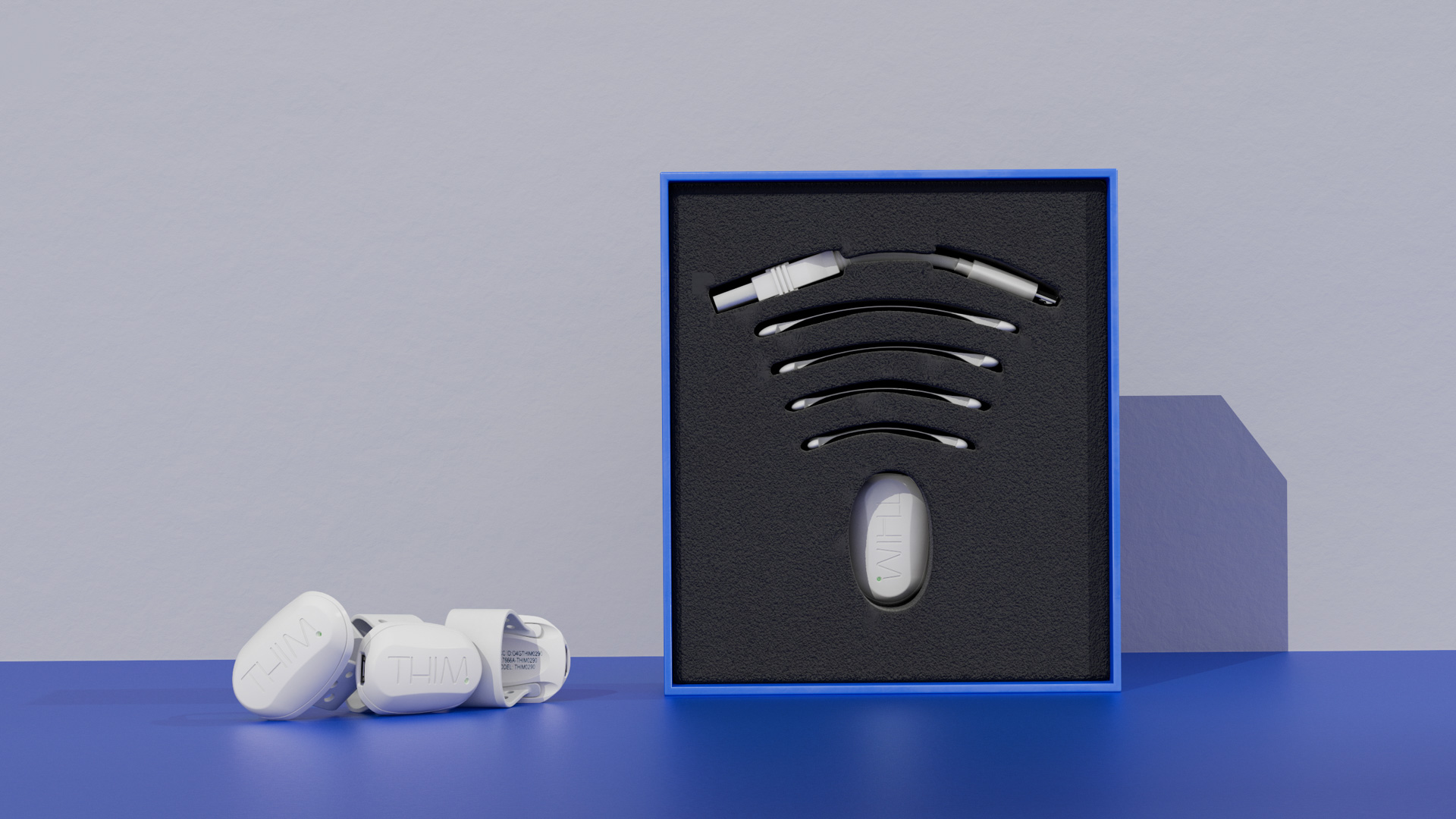 The white THIM wearable, curved straps and charging cable set in a blue box's black foam insert, three units alongside